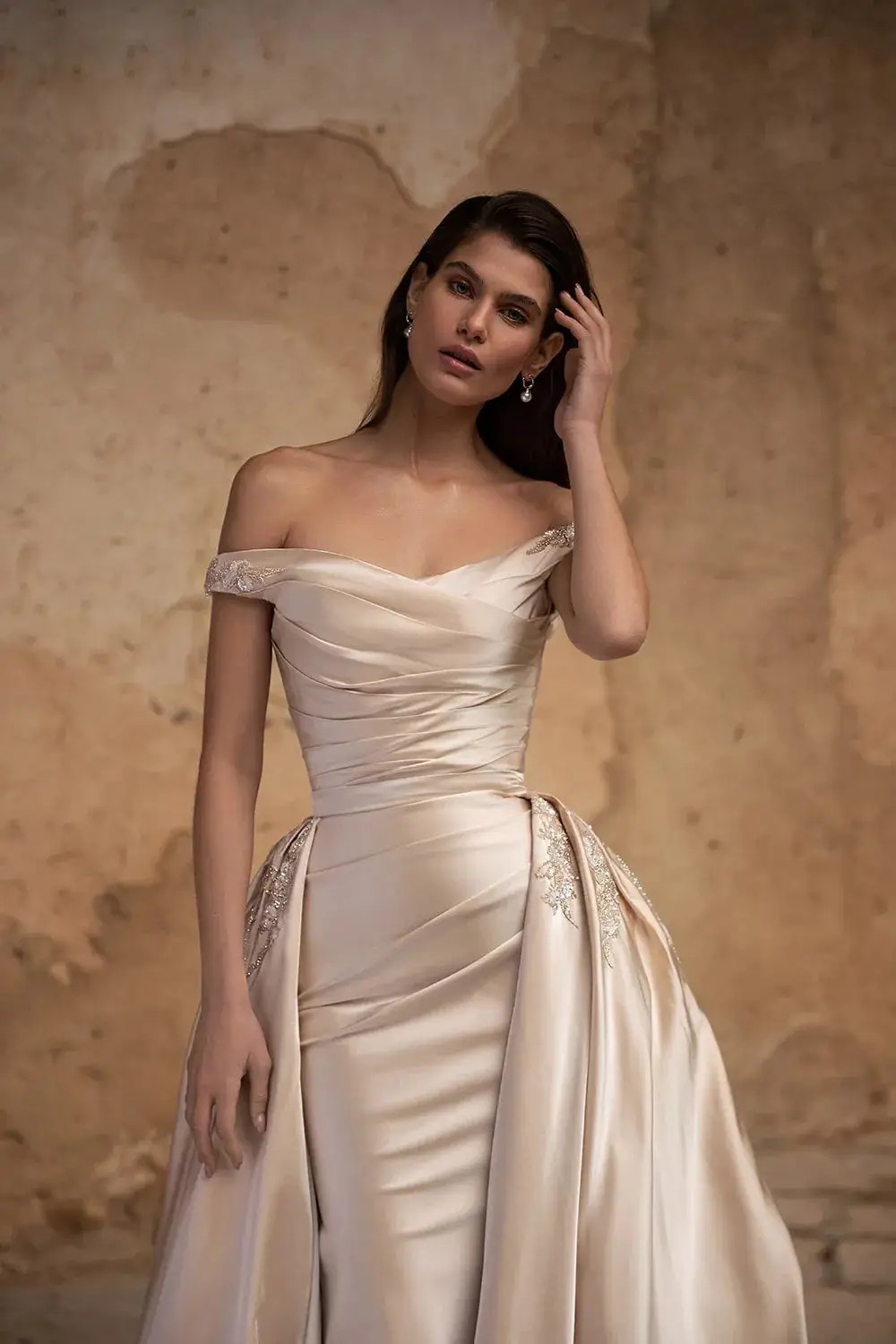 Model is wearing a satin cappuccino sheath wedding dress with an overskirt by eva lendel