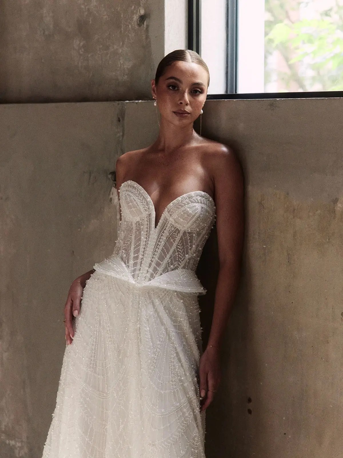Model is wearing a wedding dress with subtle sparkle, hip panels, and a basque waist by alena leena