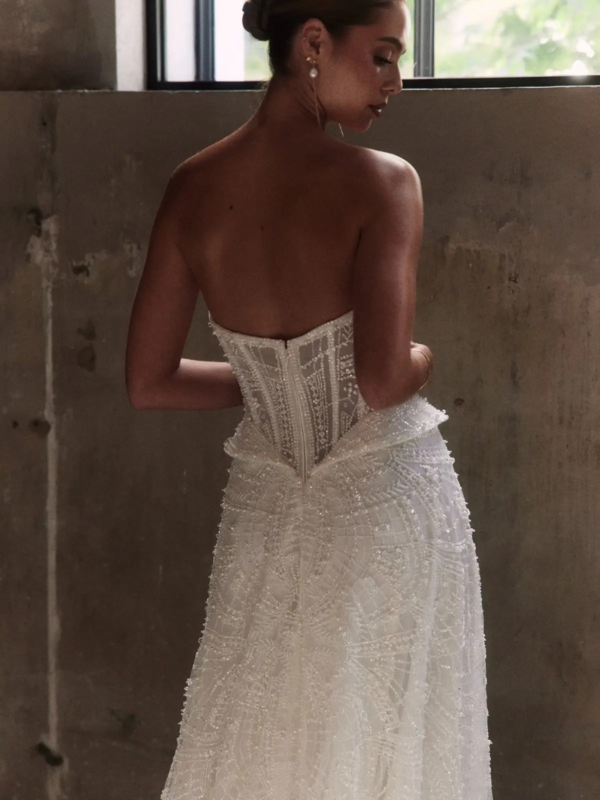 Model is wearing a wedding dress with subtle sparkle, hip panels, and a basque waist by alena leena