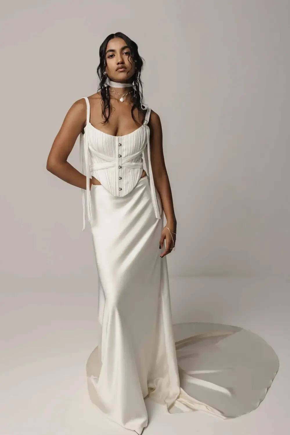 Model wearing a white elegant dress with a fitted bodice and flowing skirt, posing against a neutral background.