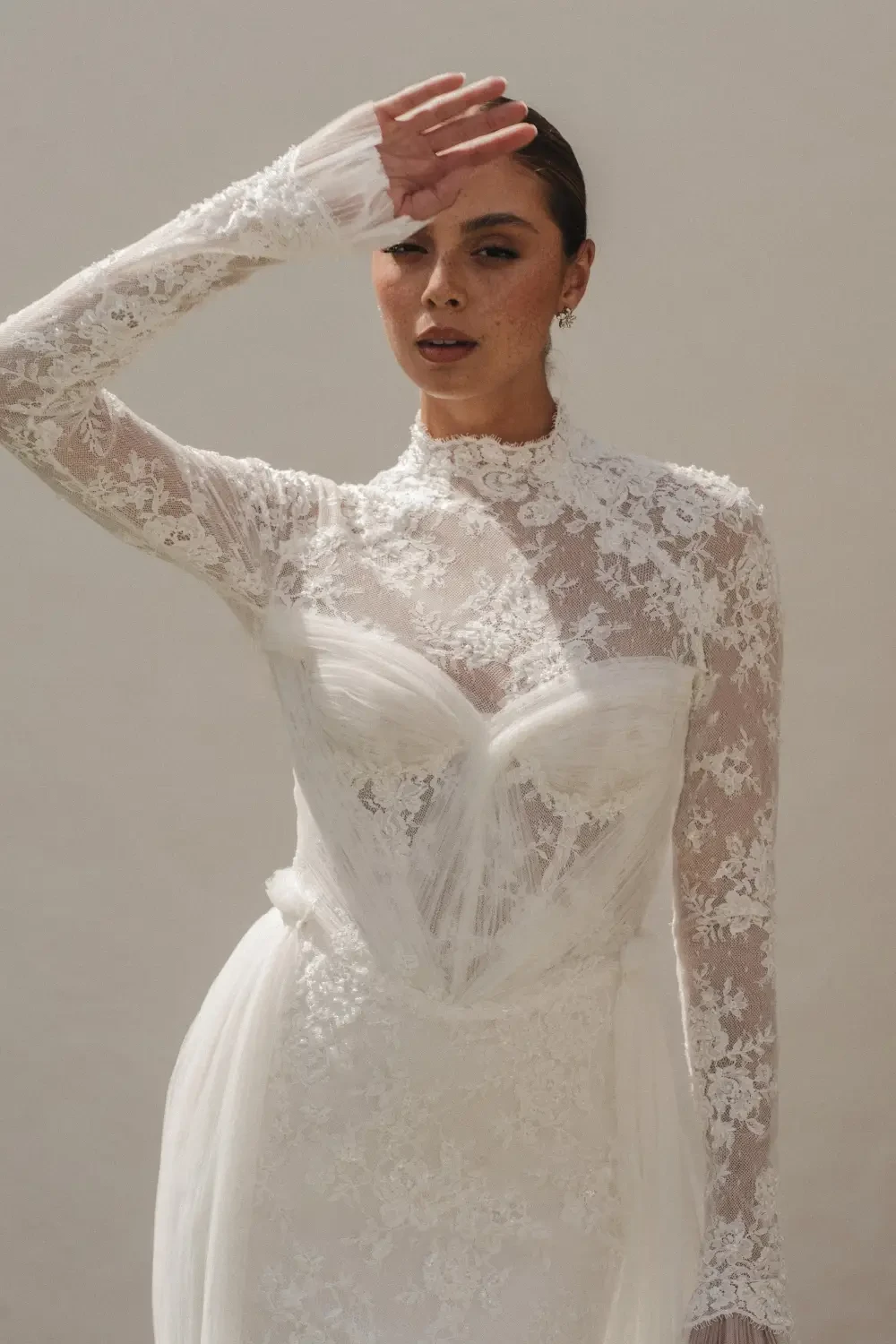 model is wearing a lace high neckline long sleeve bridal gown